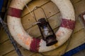 Antique rescue buoy hanging on wooden wall of a boat with old petrol lamp and artificial spider net Royalty Free Stock Photo