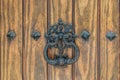 An antique rusted door handle on a weathered wooden door