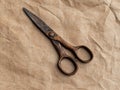 Antique rusty scissors on crumpled brown paper background