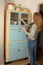 Antique 1950\'s kitchen larder cabinet in pale blue and cream. A lady opens a door to return a jar. Royalty Free Stock Photo