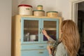 Antique 1950's kitchen larder cabinet in pale blue and cream. A lady returns a glass jar.