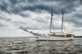 Antique sailing frigate of white color to the sea, the lowering storm sky, sails are lowered, masts and ropes Royalty Free Stock Photo