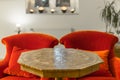 Antique side table with intarsia and red chair