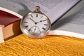 Antique silver pocket watch on background of an open book with text. Round vintage clock near old books with red and Royalty Free Stock Photo