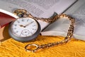 Antique silver pocket watch with gold chain lying on pages open book with text. Round grey vintage clock near old books Royalty Free Stock Photo