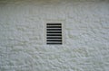 Antique slatted window in whitewashed colonial stone barn.