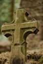 Antique stone cross situated on a gravel pathway in a tranquil park, surrounded by lush greenery