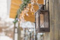 Antique street iron lantern hanging on the wooden post of a house decorated with glowing garlands outside