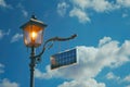 Antique Street Lamp Illuminated with Solar Panel Under Blue Sky with Clouds Royalty Free Stock Photo