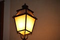 Antique style lamppost lantern attached to wall of building. Light on