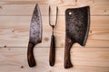 Antique stylized butcher`s set. Cleaver, knife and fork on a wooden background. View from above