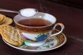 Antique tea cup full of tea with sugar and crackers on wooden ta Royalty Free Stock Photo