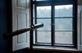 An antique telescope in front of window.