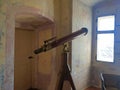 An antique telescope in a very old house, pointing out the window at the sky