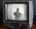 Antique television set with a silhouette of a person with a detailed face projected on the screen