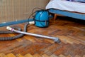 Blue vacuum cleaner stands on old parquet floor