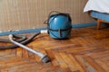 Blue vacuum cleaner stands on old parquet floor