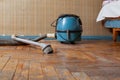 Blue vacuum cleaner stands on old parquet floor