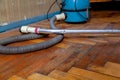 Blue vacuum cleaner stands on old parquet floor