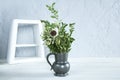 Antique vase with green plants flowers. White frame. On wooden background Royalty Free Stock Photo