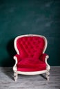 Antique velvet red armchair near emerald wall. red armchair Isolated on green background. Vintage chair on living room. furniture