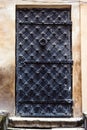 Antique vertical front door to the Middle Ages. Ancient aged closed vintage retro gothic grunge black iron metal door gate in old Royalty Free Stock Photo