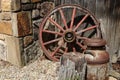 Antique wagon wheel, its wood and metal spokes weathered by time, next to a wall of an old building