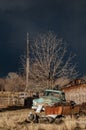 Antique warm front lit rusty light blue pickup truck sits near a rusty junk pile