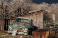 Antique warm front lit rusty light blue pickup truck sits near a rusty junk pile Royalty Free Stock Photo