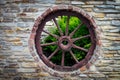 Antique and weathered wood cart wagon wheel in old stone farm bu Royalty Free Stock Photo