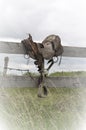 Antique western old fashioned saddle on fence in pasture Royalty Free Stock Photo