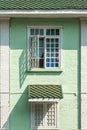 Antique white frame wooden window with light and shadow on the old green pastel brick wall exterior office building or home and Royalty Free Stock Photo