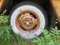 Whitewall tire on wheel of a rusty vehicle