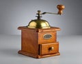 Antique wood brass coffee grinder with hand crank on grey backdrop Royalty Free Stock Photo