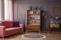 Antique wooden bookcase with decorations in an elegant gray living room interior with a comfortable powder pink sofa Royalty Free Stock Photo