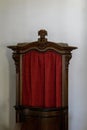 Antique confessional booth with red curtain