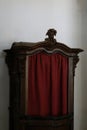 Antique wooden confessional booth with red curtain