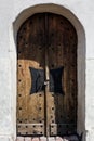 Antique wooden door with forged handle and padlock in historic building from white limestone Royalty Free Stock Photo