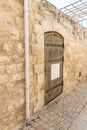 Antique wooden door with forged hinges in a stone wall on a quiet street in the old part of Safed city in northern Israel