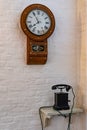 Antique wooden telephone and clock on white wall Royalty Free Stock Photo