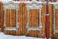Antique wooden window frame in the Russian style as decorative element on a red fence made of boards covered with snow Royalty Free Stock Photo