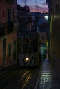 Antique yellow cable car on a narrow Portuguese street at sunset