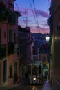 Antique yellow cable car on a narrow Portuguese street at sunset