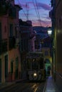 Antique yellow cable car on a narrow Portuguese street at sunset