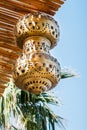 A antique yellow Turkish copper lantern under a thatched roof against a blue sky