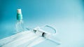 Antiseptic, medical mask and syringe on a blue background.