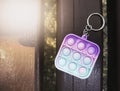 Antistress toy keychain hanging on a blue bag, on a park bench. Silicone Stress Relief Toy