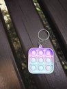 Antistress toy keychain hanging on a blue bag, on a park bench. Silicone Stress Relief Toy