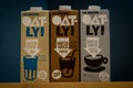 Three packs of Oatly plant-based and vegan milk, hafer, kakao and barista, on a dark background