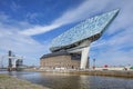 Antwerp Port headquarters against a blue sky with dramatic clouds.